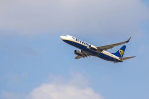 A commercial airplane flying high against a backdrop of clear blue sky, showcasing aviation excellence.